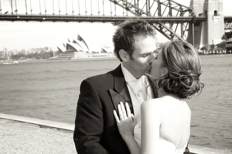 Bride and groom kissing with Sydney Harbour Bridge - wedding photography